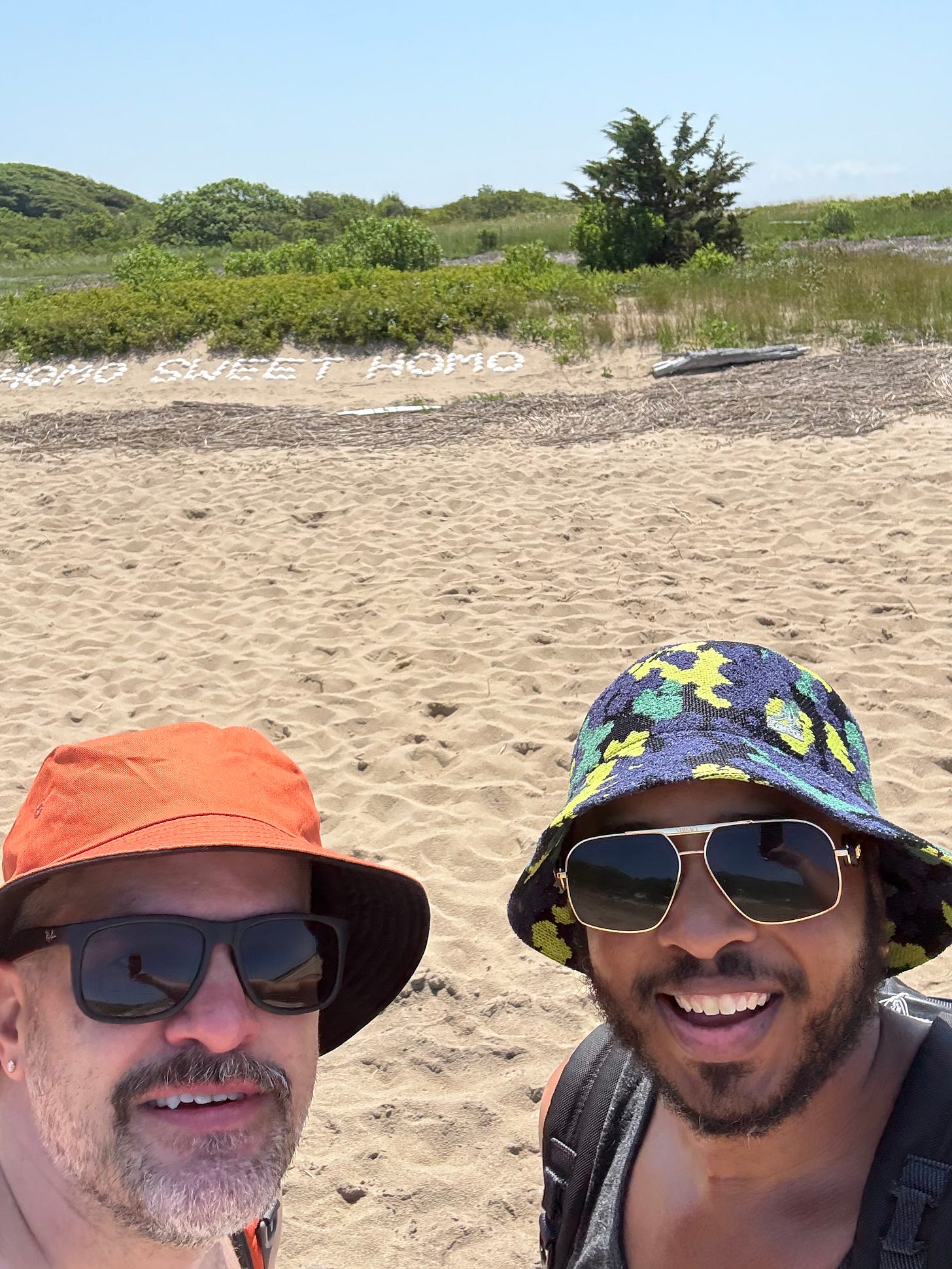 Two men in bucket hats smiling on the beach in Provincetown.